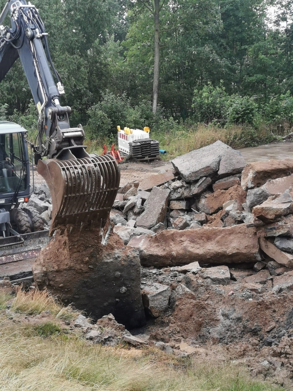 Bagger bricht Asphaltschicht auf